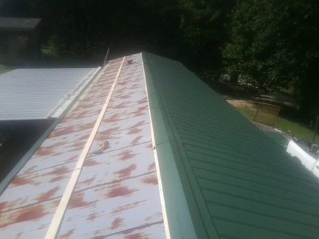 Old rusted panels beside newly installed green metal roofing — Wind Damage Roof Repair by Roofing Brothers in Trinity